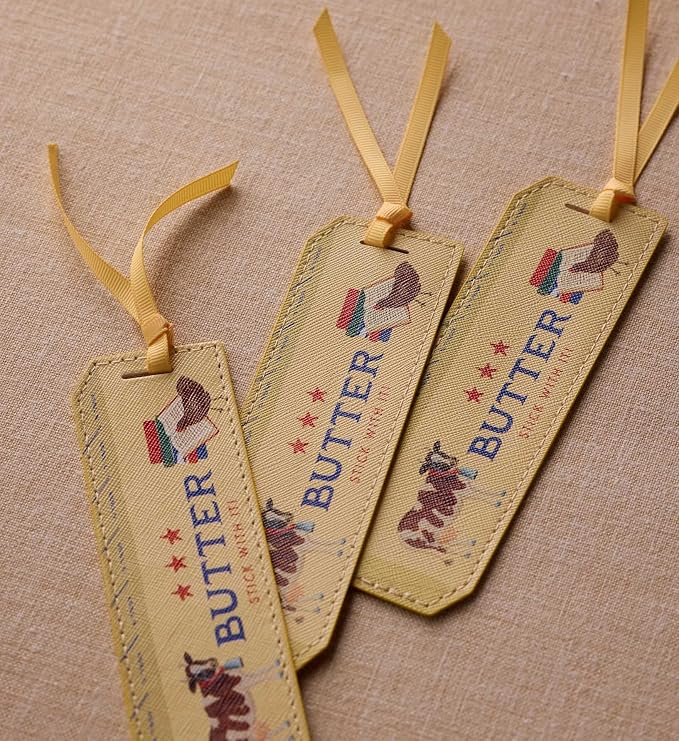 RIFLE PAPER CO. Butter Stick with It Bookmark, 1.75" W x 6" L, Playful Butter Stick with It Text, Wipe-Clean Saffiano Polyurethane, Grosgrain Ribbon, Gold Foil Logo